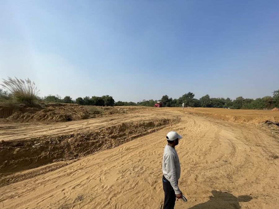 A man standing beside a freshly cut bank of sandy earth